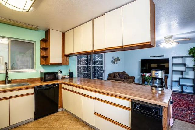 a kitchen with stainless steel appliances granite countertop a refrigerator a sink dishwasher a stove and white cabinets with wooden floor