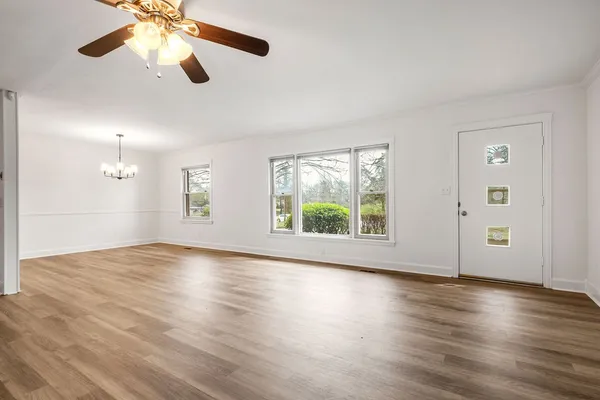 a view of an empty room with wooden floor and a window