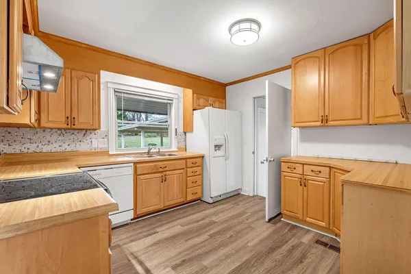 a kitchen with stainless steel appliances granite countertop a refrigerator a stove top oven cabinets and a sink
