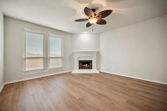 an empty room with wooden floor fireplace and windows