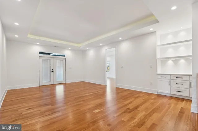 a view of an empty room with window and wooden floor