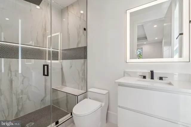 a bathroom with a sink a toilet a mirror and shower