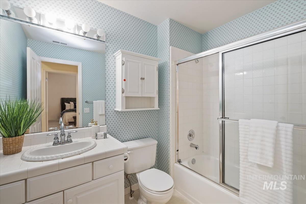 812 East Riverpark Lane Boise, ID 83706 - Photo 13 of 24 Bathroom with wallpapered walls, bath / shower combo with glass door, connected bathroom, vanity, and light tile patterned flooring