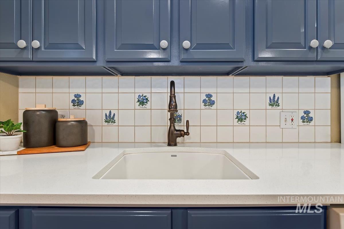 812 East Riverpark Lane Boise, ID 83706 - Photo 6 of 24 Kitchen view of blue cabinets, light stone countertops, and tasteful backsplash