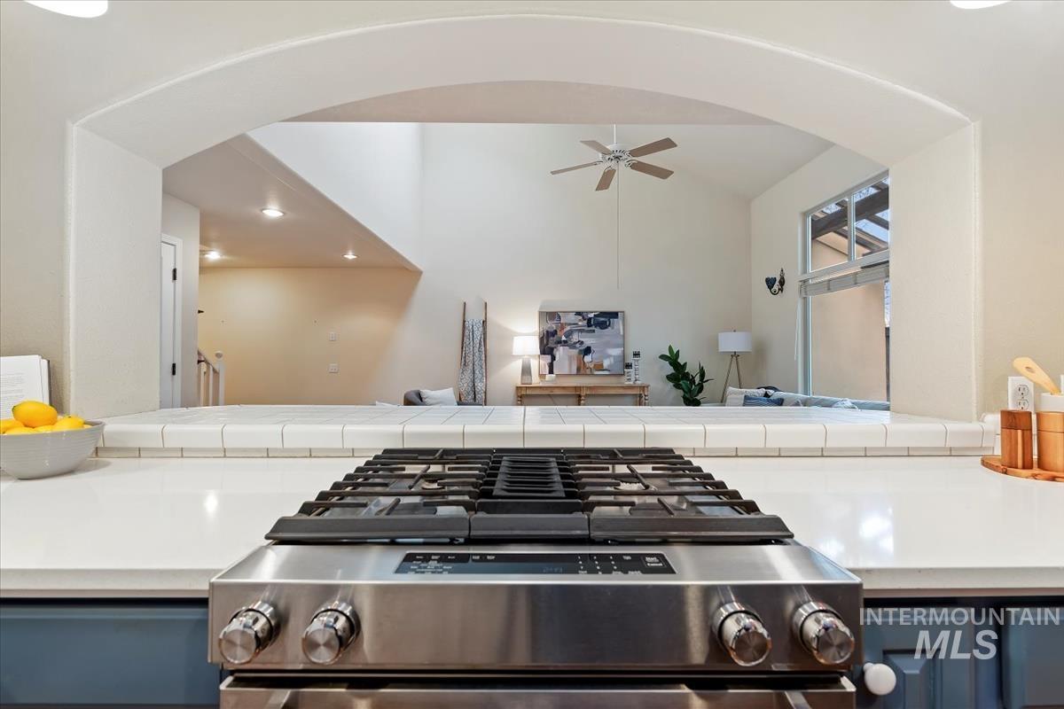 812 East Riverpark Lane Boise, ID 83706 - Photo 7 of 24 Kitchen view of blue cabinetry, stainless steel gas stove, ceiling fan, and arched walkways