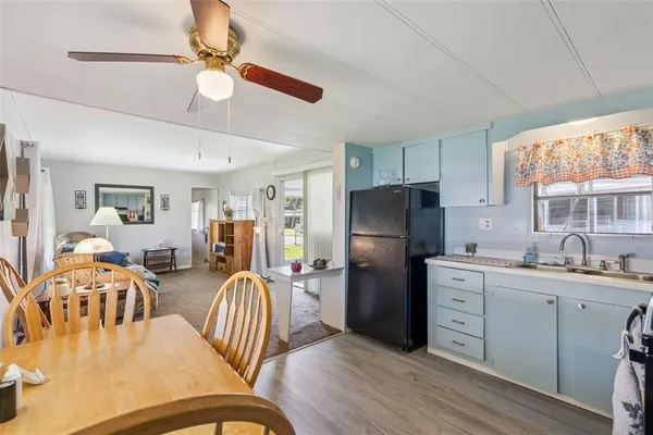 a kitchen with stainless steel appliances granite countertop a refrigerator a sink a stove a dining table and chairs with wooden floor