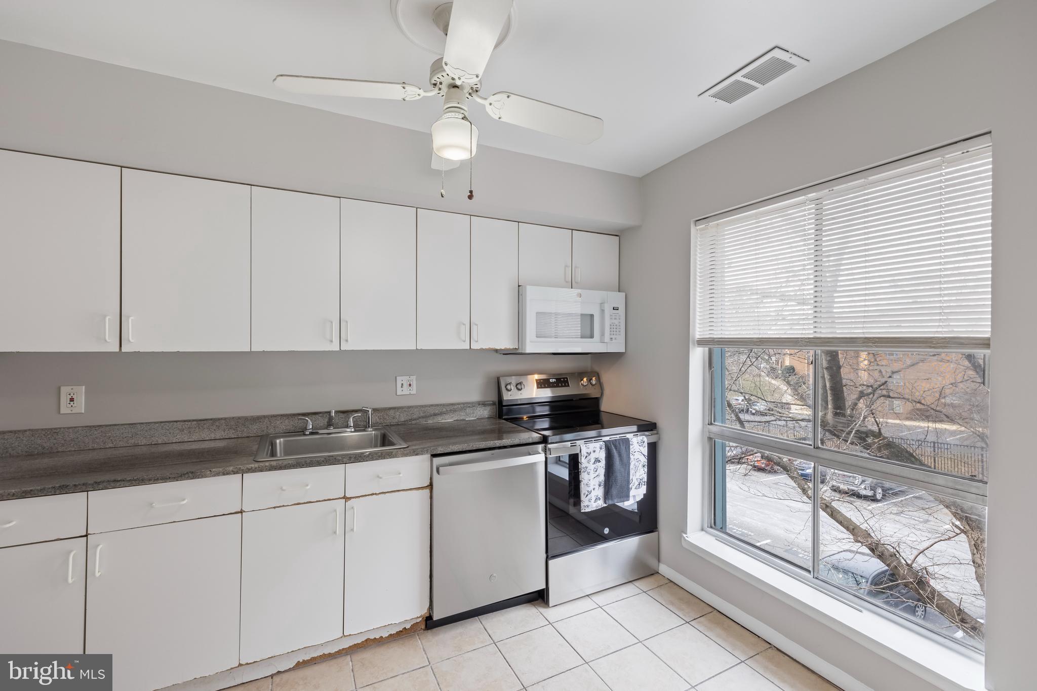 3902 Bel Pre Road, Unit 39028 Silver Spring, MD 20906 - Photo 9 of 31 a kitchen with stainless steel appliances granite countertop a stove a sink and white cabinets