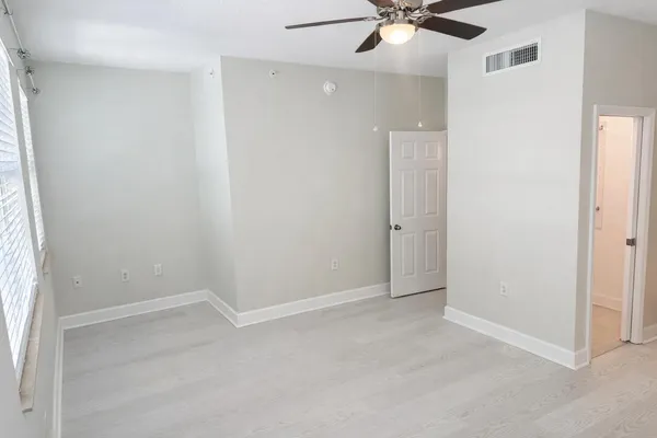 an empty room with a window and a fan