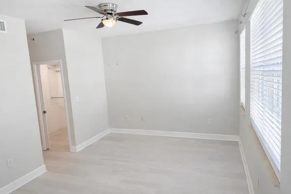 an empty room with a window and a fan