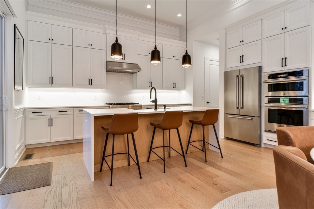 16 Barnes Boulevard, Unit 16 Hudson, MA 01749 - Photo 5 of 42 a kitchen with stainless steel appliances kitchen island a table chairs in it and wooden floors