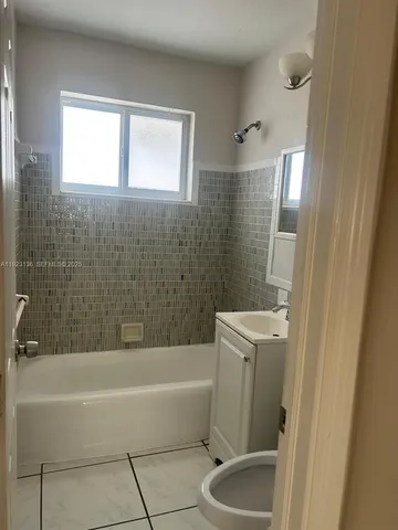 a bathroom with a tub a sink a window and a shower