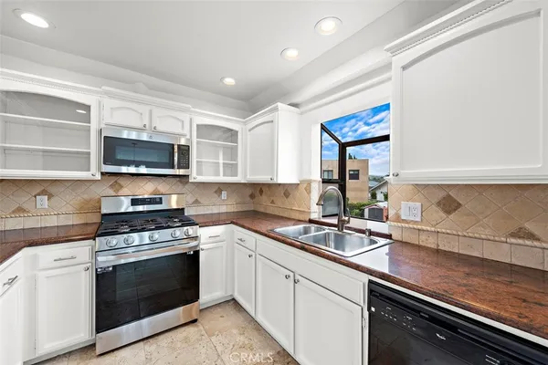 a kitchen with granite countertop a sink stainless steel appliances and cabinets