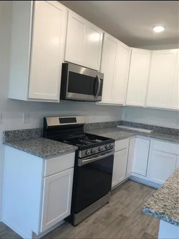 a kitchen with stainless steel appliances granite countertop a sink a stove and a microwave