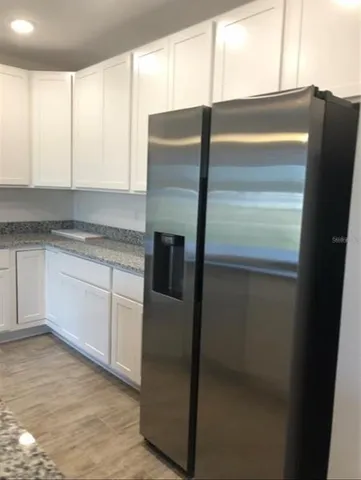 a kitchen with metallic refrigerator and white cabinets