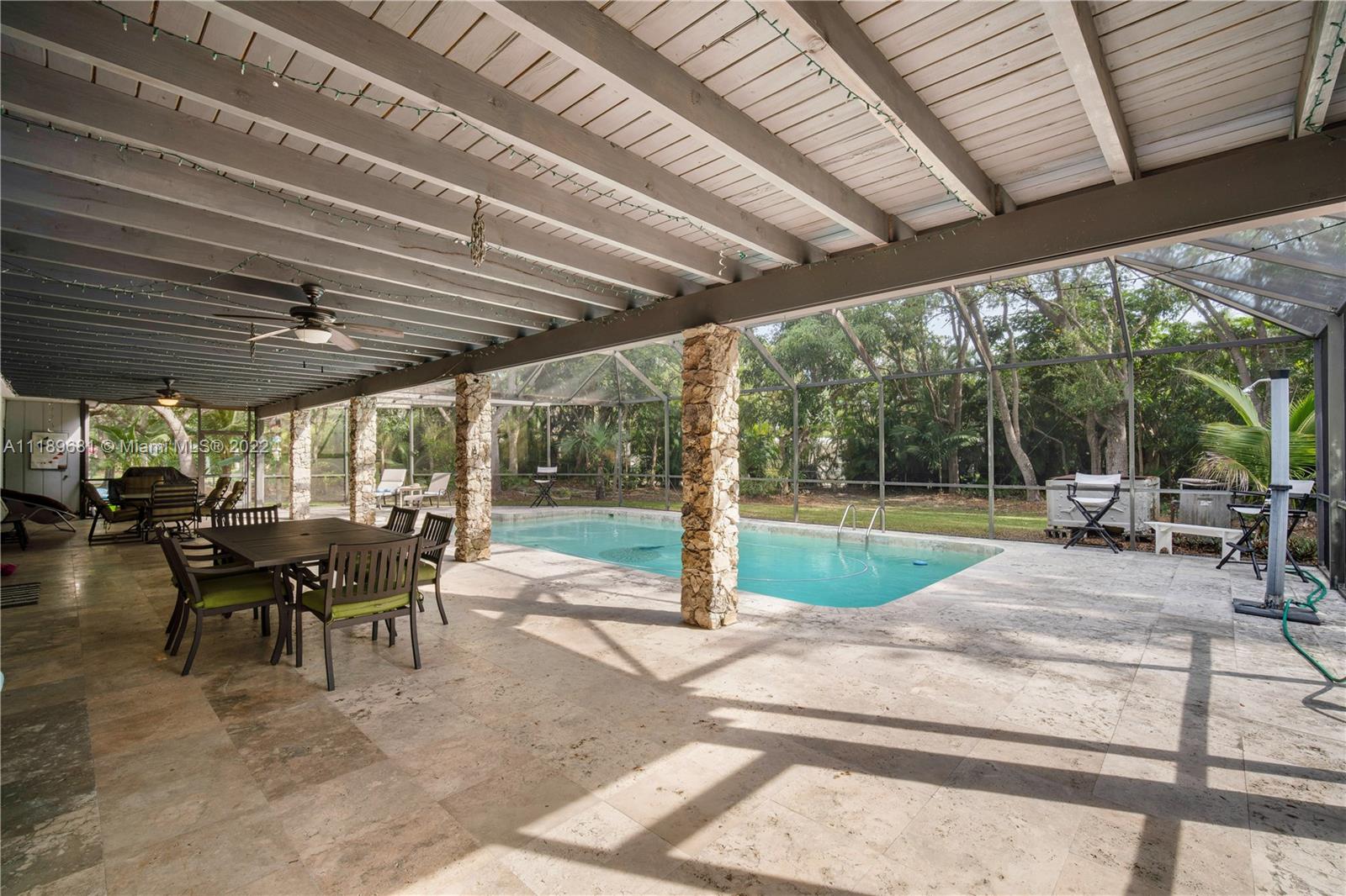 6465 Southwest 126th Street Road Pinecrest, FL 33156 - Photo 26 of 37 a view of a patio with table and chairs under a large umbrella