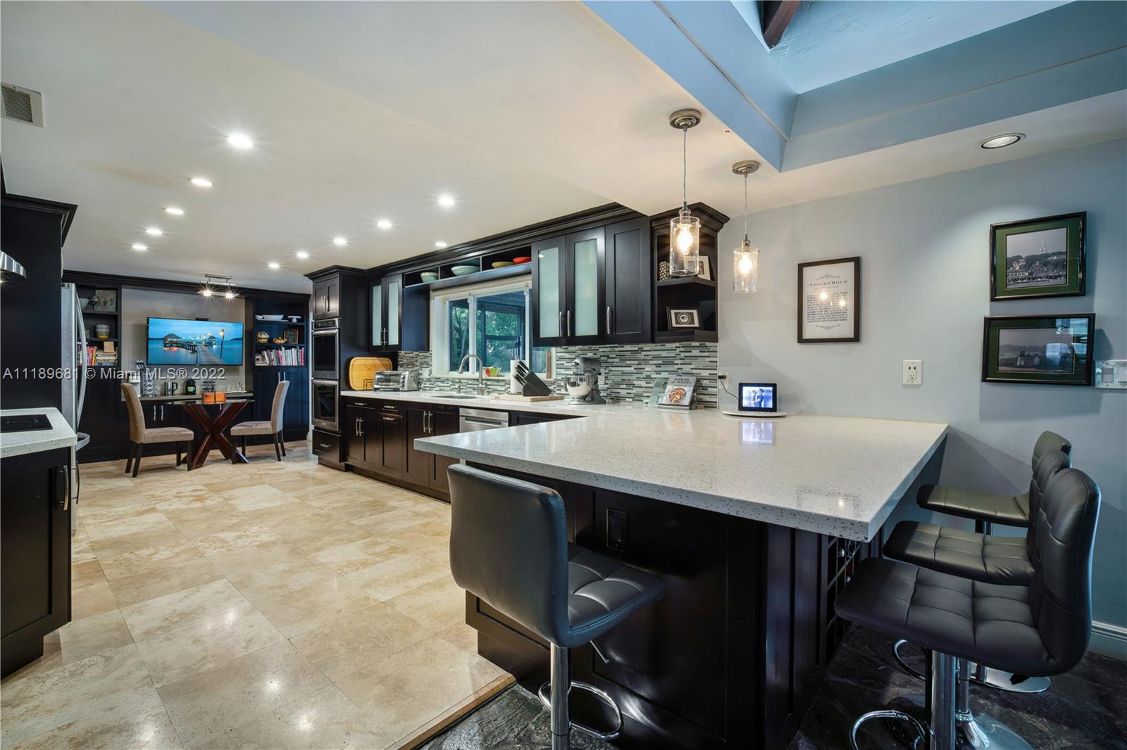 6465 Southwest 126th Street Road Pinecrest, FL 33156 - Photo 3 of 37 a kitchen with kitchen island a dining table and chairs