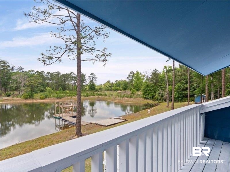 3160 Old Castleberry Road Brewton, AL 36426 - Photo 15 of 36 Private deck with white railing overlooking a tranquil pond, featuring a multi-level wooden dock and a small blue shed on the shoreline