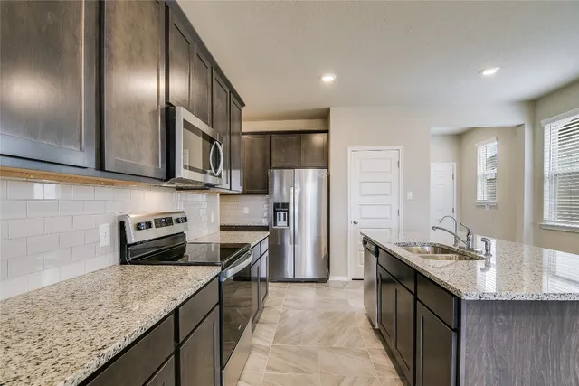 a kitchen with stainless steel appliances granite countertop a sink a stove and a refrigerator