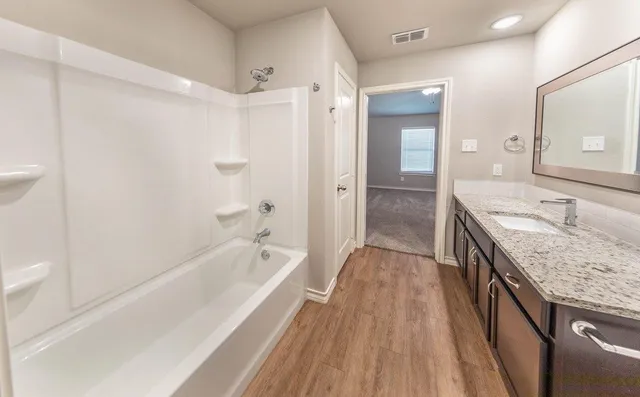 a spacious bathroom with a granite countertop tub sink and mirror