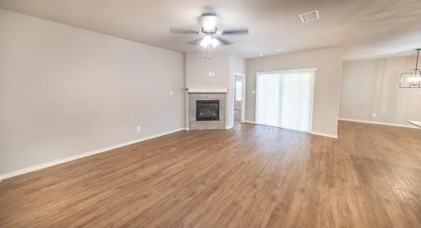 a view of an empty room with wooden floor fireplace and a window