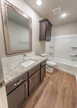 a bathroom with a granite countertop sink toilet and mirror