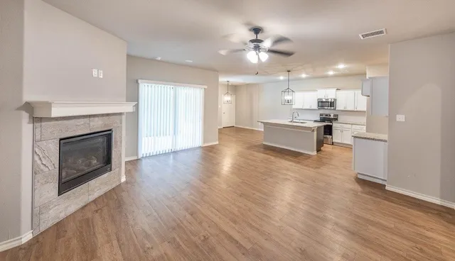 a large living room with stainless steel appliances a fireplace and chandelier