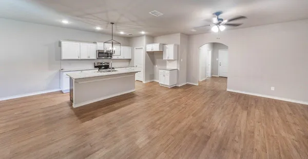 a large white kitchen with kitchen island a sink dishwasher a stove and a refrigerator with wooden floor