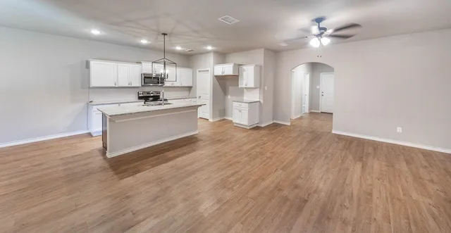 a large white kitchen with kitchen island a sink dishwasher a stove and a refrigerator with wooden floor