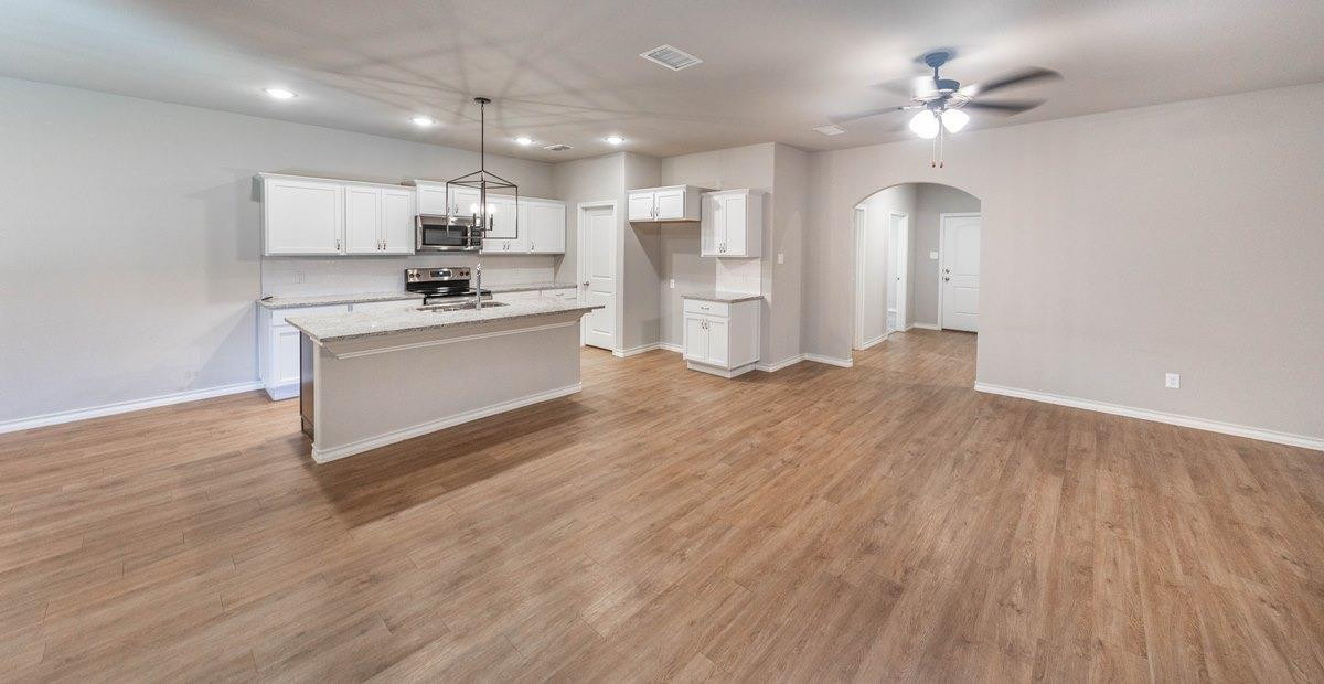 2545 137th Street Lubbock, TX 79423 - Photo 5 of 26 a large white kitchen with kitchen island a sink dishwasher a stove and a refrigerator with wooden floor