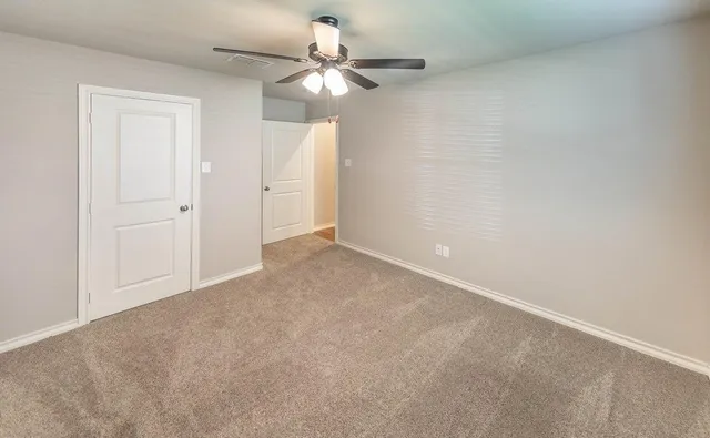 an empty room with a chandelier fan and closet area