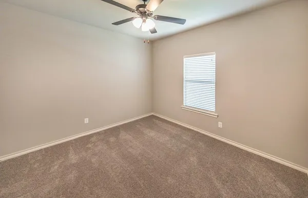 an empty room with a window and ceiling fan