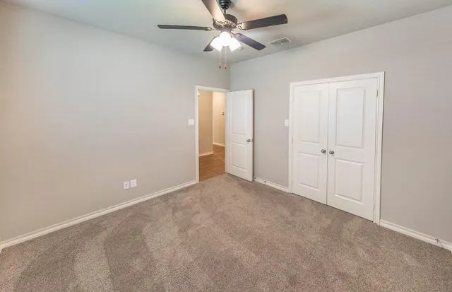 an empty room with closet and a chandelier fan