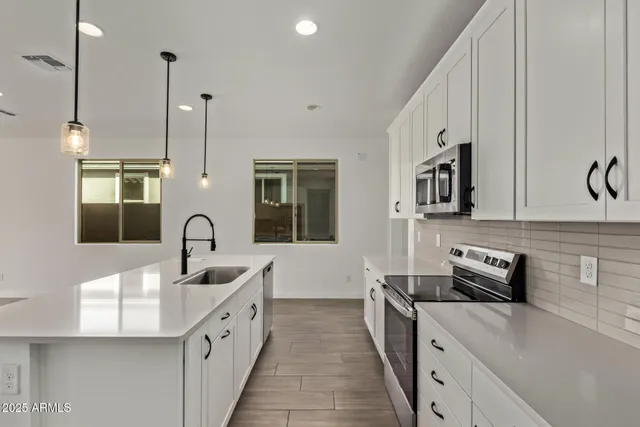 a kitchen with stainless steel appliances granite countertop a sink a stove and a refrigerator