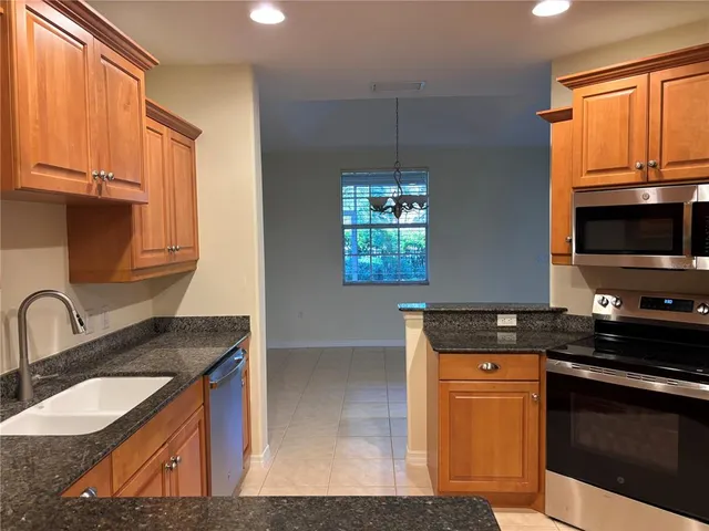 a kitchen with granite countertop a sink a stove and a microwave