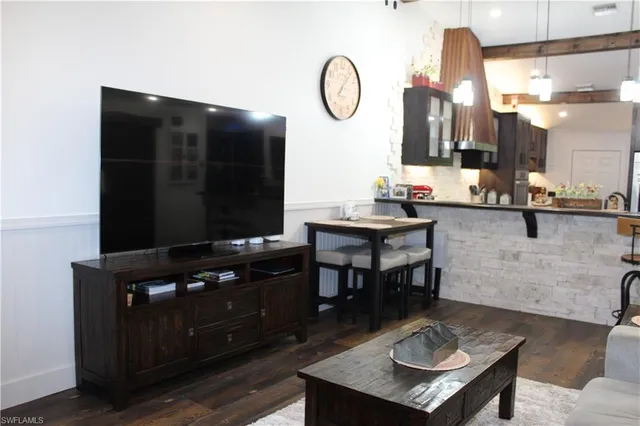 a living room with furniture a flat screen tv and kitchen view