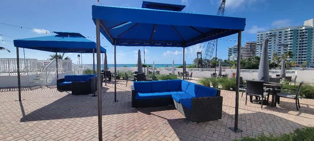 5401 Collins Avenue, Unit 214 Miami Beach, FL 33140 - Photo 29 of 37 a view of a patio with a dining table and chairs under an umbrella