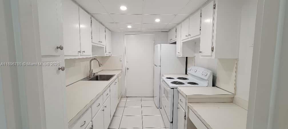 5401 Collins Avenue, Unit 214 Miami Beach, FL 33140 - Photo 10 of 37 a kitchen with white cabinets and refrigerator