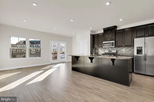 a kitchen with stainless steel appliances granite countertop a refrigerator a sink a stove a microwave and wooden floors