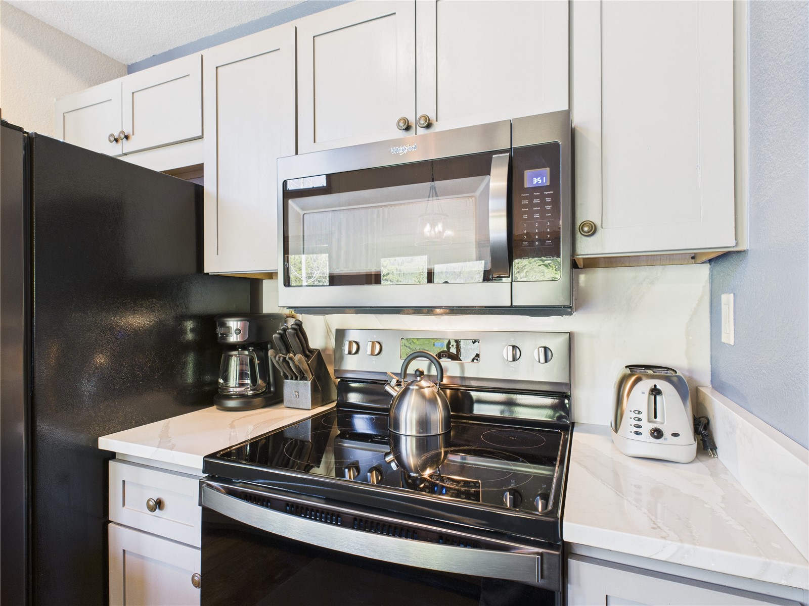 27 Lake Ridge Circle, Unit 1842 Keystone, CO 80435 - Photo 10 of 50 Modern stainless stove, microwave, drip coffee maker, toaster, and cutlery—fully equipped for all your cooking needs.