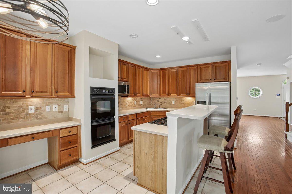 7301 Oldham Leeds Way Springfield, VA 22150 - Photo 3 of 34 a kitchen with a refrigerator a stove top oven a sink dishwasher and wooden cabinets with wooden floor