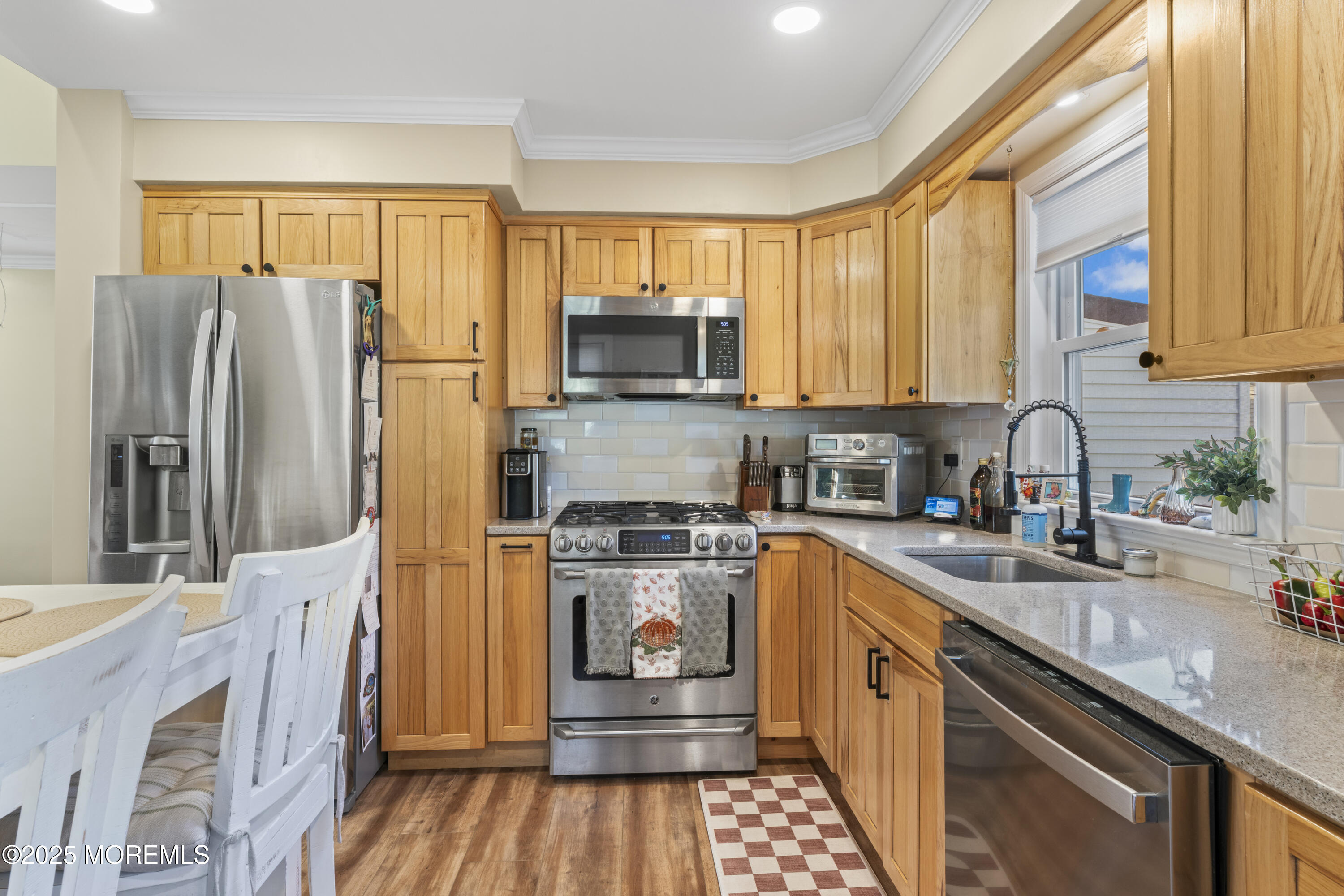 240 Timberline Road Toms River, NJ 08753 - Photo 15 of 25 a kitchen with stainless steel appliances granite countertop a refrigerator a sink dishwasher a stove and a dining table with wooden floor