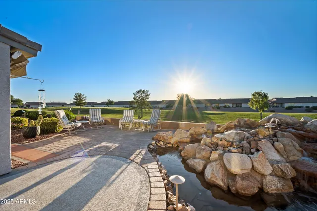 a view of a backyard with lawn chairs floor to ceiling window and wooden fence