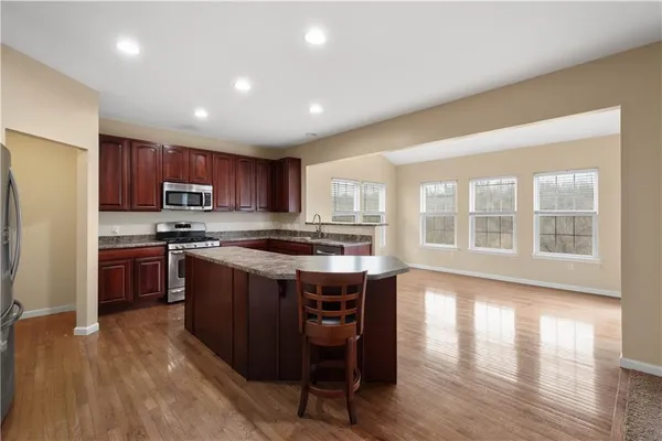 a kitchen with stainless steel appliances granite countertop wooden floors and wooden cabinets