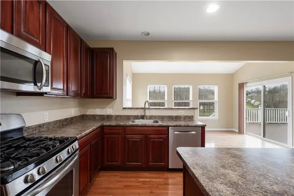 a kitchen with stainless steel appliances granite countertop wooden cabinets a stove top oven a sink and dishwasher