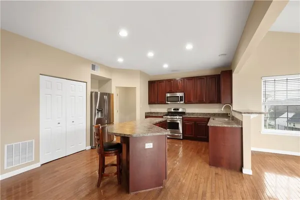 a kitchen with stainless steel appliances granite countertop wooden floors a stove and a refrigerator
