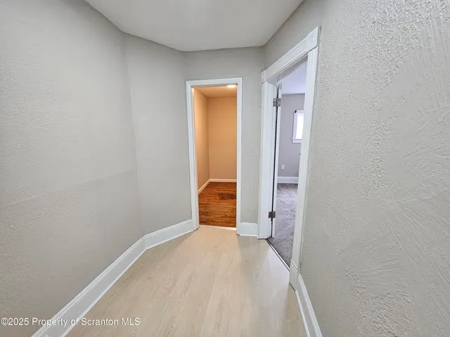 a view of a hallway with wooden floor and a bathroom