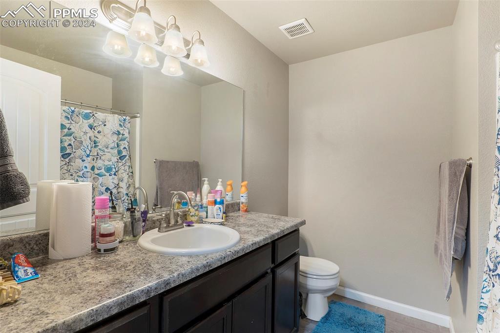 4346 Yellow Dock Point Colorado Springs, CO 80911 - Photo 14 of 20 a bathroom with a granite countertop sink a toilet and a mirror