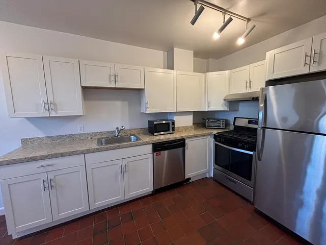 a kitchen with stainless steel appliances granite countertop a refrigerator sink and cabinets