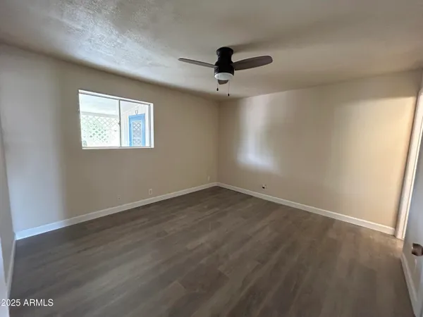 an empty room with wooden floor ceiling fan and windows