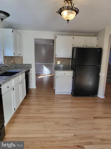 a kitchen with stainless steel appliances wooden floor sink and cabinets
